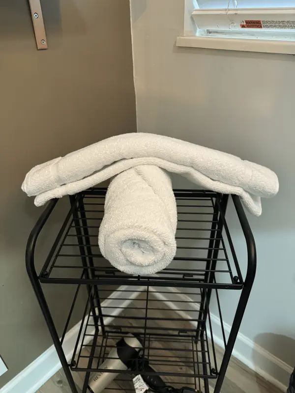 Rolled and folded white towels on a bathroom cart