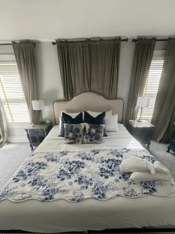 Bedroom with a freshly made bed, blue floral quilt and folded towels