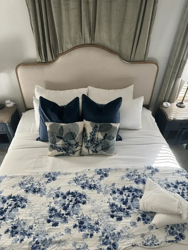 Close-up of a made bed with navy and botanical pillows
