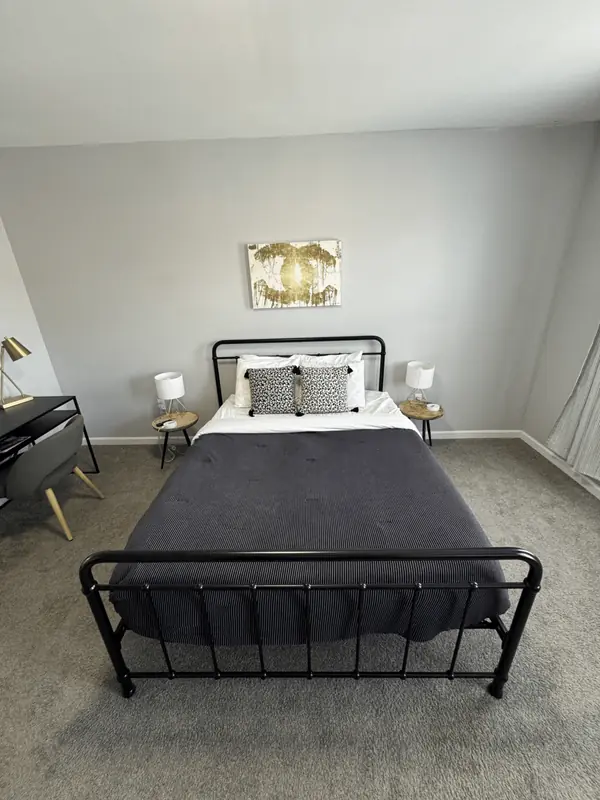 Bedroom with a black iron bed, striped comforter and work desk