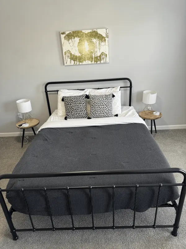Made bed with leopard print pillows between two nightstands