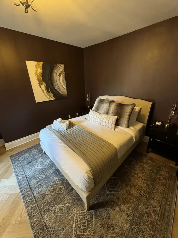 Cozy bedroom with a made bed, fur pillows and patterned rug