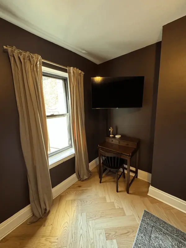 Bedroom corner with a writing desk, wall TV and velvet curtains